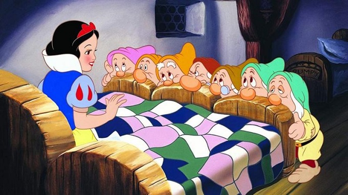 Blancanieves sentada en la cama delante de los siete enanitos