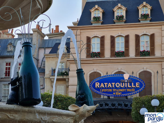Escultura de Rémy decorchando una botella en la fuente frente al cartel de Ratatouille