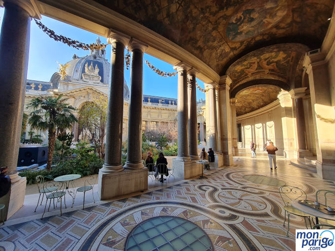 Galería y patio del Petit-Palais en París con el techo pintado, suelo con mosaicos y mesas