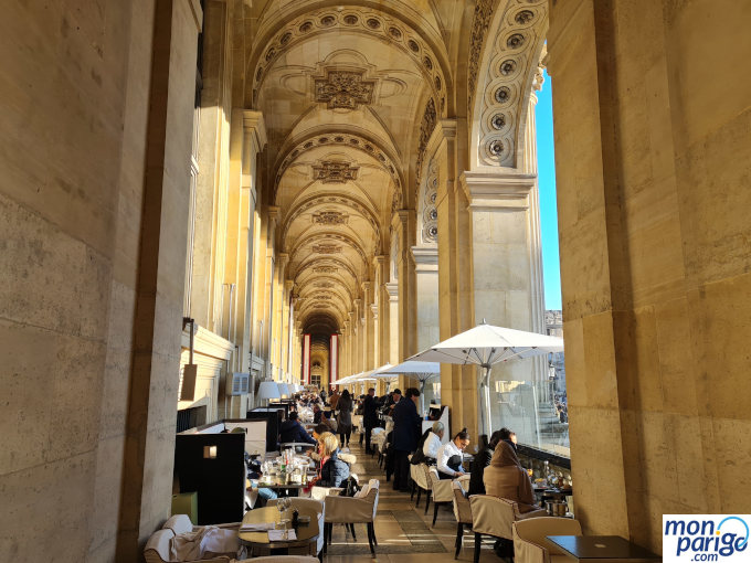 Mesas de la terraza del Café Marly en París bajo los arcos de la galería