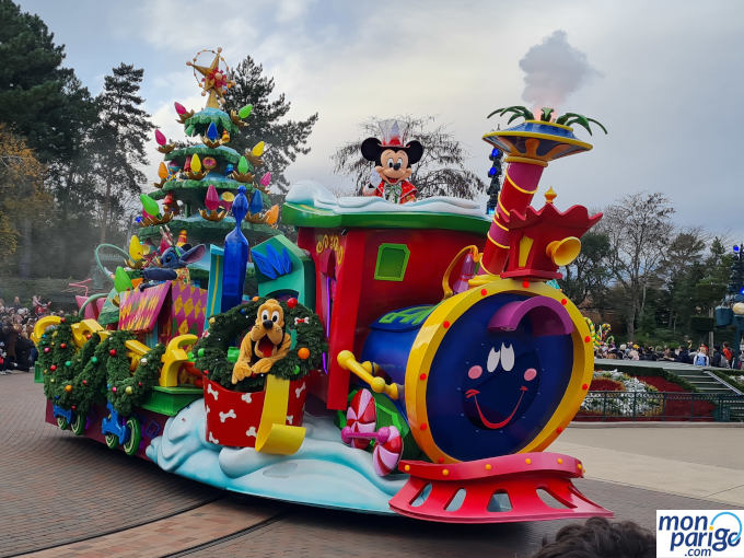 Mickey y Pluto en una carroza con forma de tren y con un árbol de Navidad