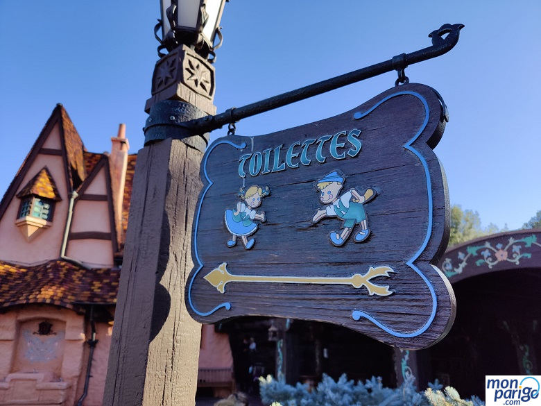 Cartel de madera con la palabra "Toilettes" y una flecha en Disneyland Paris