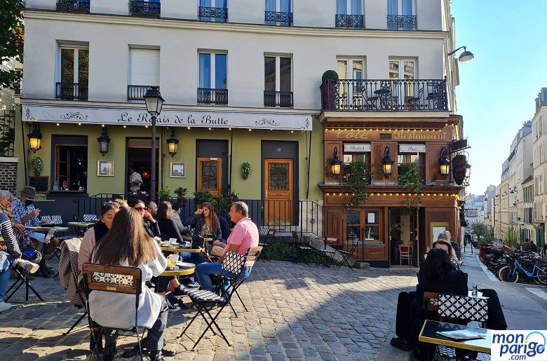 Gente tomando algo en una terraza de una plaza de París