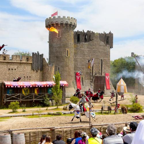 Lanzas y soldados a caballo frente a una muralla del castillo en llamas