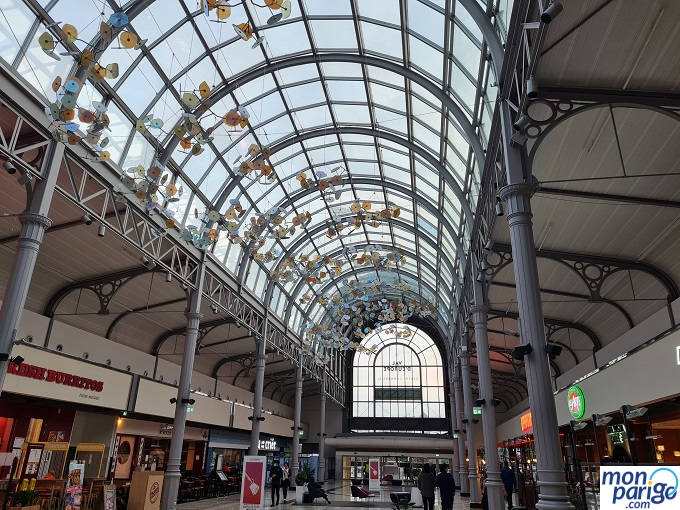 Calle interior con estructura de metal y techo de cristal en el centro comercial Val d'Europe junto a Disneyland Paris
