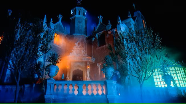 Casa encantada iluminada inmersa en la niebla en el parque Magic Kingdom Orlando
