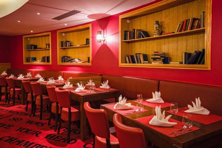 Mesas preparadas y suelo de moqueta roja en el restaurante  del hotel Explorers de Disneyland Paris