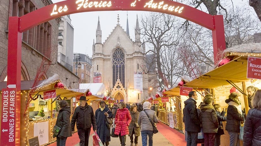 Gente caminando entre los puestos del mercado de Navidad Les Féeries d' Auteuil en París