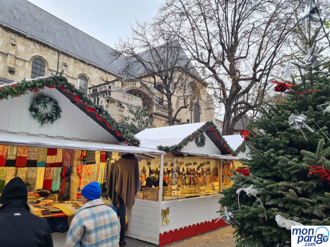 Mercado navideño con casetas de madera y un árbol de Navidad frente a la iglesia de París