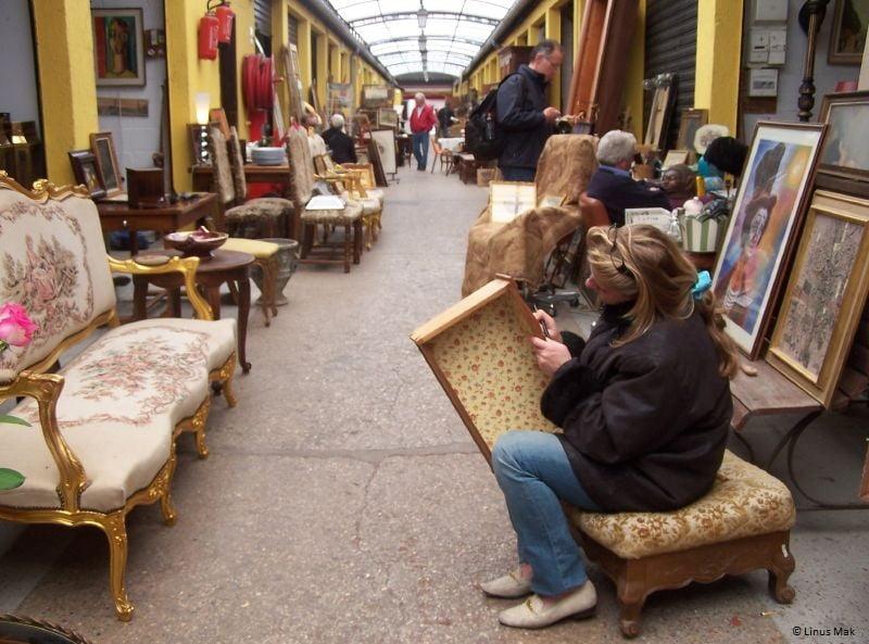 Un anticuario trabajando en un pasillo del mercado de las Pulgas en París
