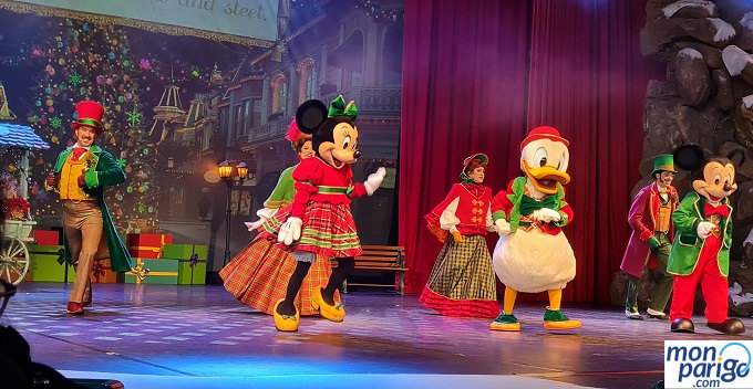 Mickey, Minnie y Donald sobre un escenario bailando junto a bailarines en el musical de Navidad en Disneyland Paris
