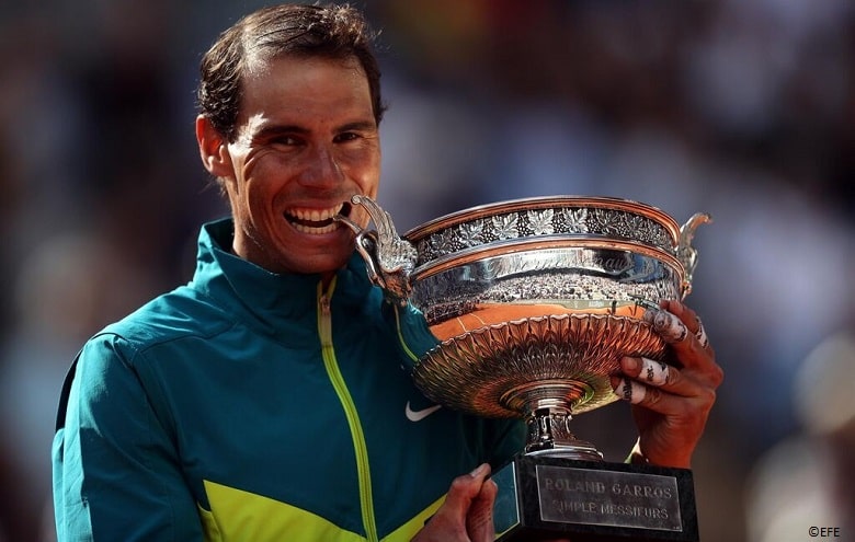 Tenista Rafa Nadal mordiendo la Copa de los Mosqueteros en Roland Garros París