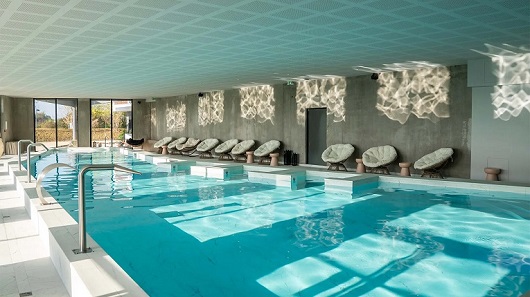 Zona de piscina cubierta y spa en el moderno Ki Space Hotel & Spa, un hotel asociado de Disneyland Paris.