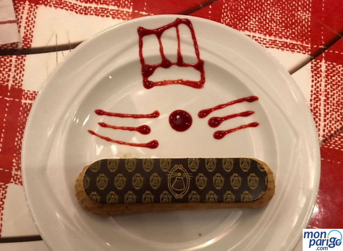 Eclair de chocolate decorado  con mermelada de fresa para dibujar una rata con gorro de chef