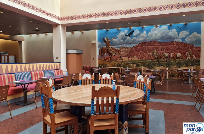 Mesas con sillas y un gran cuadro de indios a caballo en el comedor del restaurante del hotel Santa Fe de Disneyland Paris