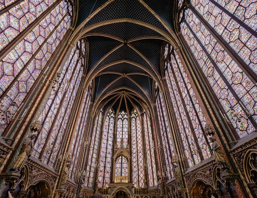 Interior gótico de la Sainte-Chapelle con impresionantes vitrales y techo azul con estrellas doradas en París.