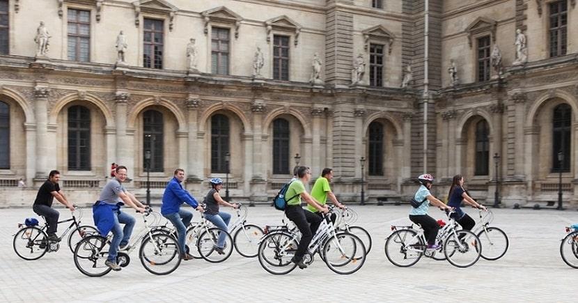 Grupo guiado en bici pasando por el patio de un monumento de París