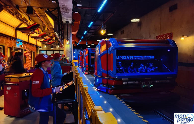 Vehículo rojo en la zona de embarque con visitantes y personal dentro de Spider-Man W.E.B. Adventure de Disneyland Paris